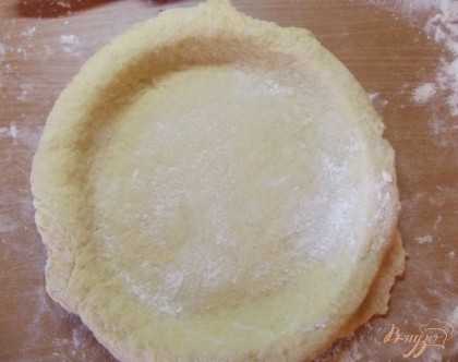 Раскатайте тесто в круглый корж диаметром большим чем диаметр формы на десять сантиметров. Укройте форму тестом и посыпьте немного сахаром.