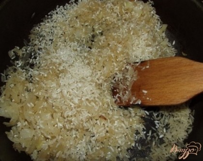 Когда лук станет мягким засыпаем к нему сырой рис. При этом поверх риса доливаем примерно три столовые ложки оливкового масла, перемешиваем чтобы оно покрыло всю массу риса и после немного солим. Обжариваем пока рис не станет коричневым, постоянно перемешивая и, по необходимости, подливая оливковое масло.
