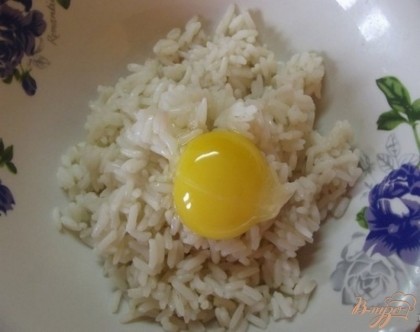 Когда рис остынет, переложите его в мисочку и вбейте одно яйцо.