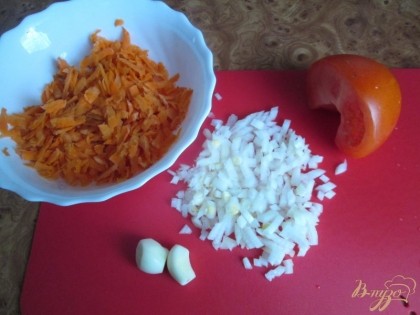 В начале нужно подготовить все ингредиенты. Потереть на терке морковь, мелко порезать репчатый лук, почистить два зубчика чеснока, порезать помидор и отварить рис в подсоленой воде.