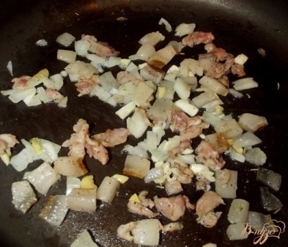 На разогретую сухую сковородку высыпаем свиное сало и ждем пока оно начнет таять. Когда от сала на сковородке появится жирок высыпаем в нее бараний жир с мясом. Также добавляем перец и базилик. Внимание: солить не нужно в том случае, если вы используете уже засоленное сало. Если пресное - чуток посолите. Когда на сковородке появиться достаточно жира высыпьте лук и чеснок. Хорошо перемешайте и накройте крышкой. Уменьшите огонь до минимума и на 10 минут забудьте про сковородку.