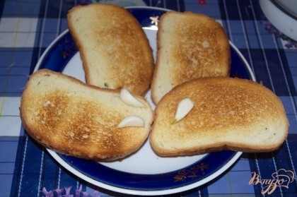 Подрумянить в тостере. Готовлю гренки именно в тостере, чтоб не перенасыщать их лишним жиром. Натрите каждую гренку с одной стороны немного чесноком. Даже на завтрак, его сильно слышно не будет. Два зубца хватает на целый батон.