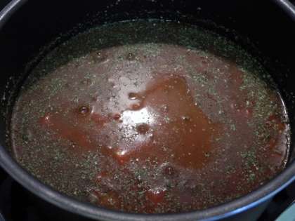 В глубокую кастрюлю вылить помидоры в собственном соку, добавить зелень и соль
