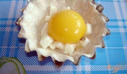 На тесто выложить нарезанный сулугуни. Яйца могут быть разного размера. Чтоб при выпекании яйца не превысили пределы кокотницы и не залили духовку, поступим так: 1) Возьмите стакан и 1 яйцо 2) Разбейте яйцо и вылейте белок в стакан 3) Желток должен остаться целым в скорлупе 4) Высадите желток на сулугуни 5) Теперь долейте белок столько, сколько позволяет форма. Лишний белок останется в стакане. 6) Лишний белок можно использовать для следующей порции или для другого блюда.