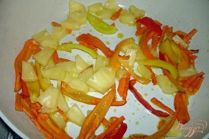 На хорошо разогретой сковороде обжарить морковь. Когда она слегка станет мягкой, доюавьте болгарский перец. Жарим без крышки 5 минут. Теперь добавляем нарезанные ананасы. У меня ананасы кружками-кольцами. Каждое кольцо я разрезала на 12 частей. Получились вполне удобные для поедания кусочки. Кусочки ананаса не должны быть слишком крупные. Жарим овощи, вместе с ананасами, еще 3 минуты.