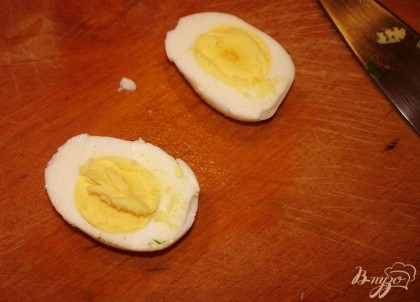 Залейте отваренные яйца холодной водой. Слегка стукните каждое яйцо о что-то ( скарлупа треснет). Верните в воду.  Это позволит легче снять скорлупу. После остывания очистить яйца. Каждое яйцо разрезать пополам. Вынуть желток.