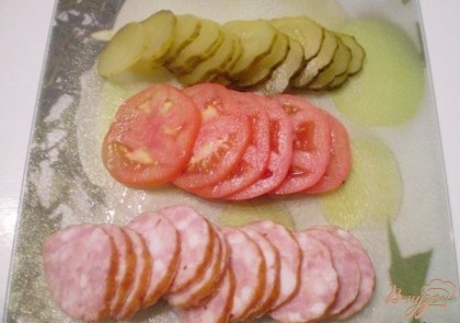 Порежьте маринованный огурец, помидор и колбасу кольцами.
