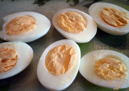 Режем яйца на половинки. Осторожно, чтобы не повредить яичные корзинки вынимаем кофейной ложечкой или чистыми руками желтки. Отставляем белки с сторону, они пока не понадобятся. Займемся начинкой.