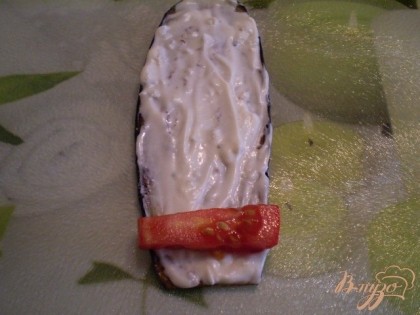  На каждый листочек баклажана смазанный пастоподобным сыром с чесноком выкладывайте по кусочку помидора. Сворачивайте в рулетик.