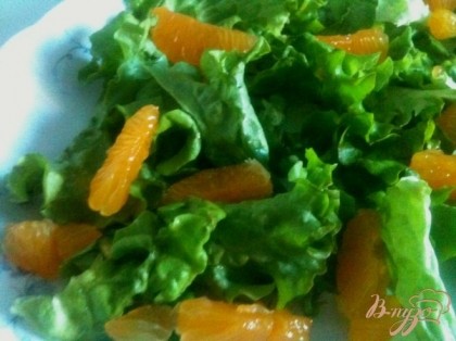 По тарелкам разложить салатные листья и дольки мандарина.