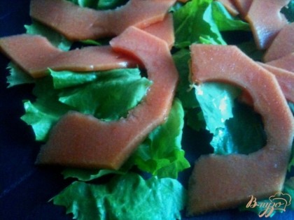 По  тарелкам разложить листья салата и кусочки папайи.