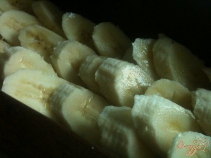 В форму для выпечки кексов пыложить половину теста и кусочки банан.
