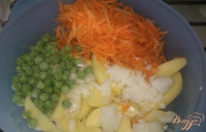 Теперь занимаемся овощами. Молодой картофель очищаем и нарезаем продолговатыми дольками (можно крупными кубиками или брусочками). Морковь чистим и натираем на крупной терке. Репчатый лук также избавляем от кожуры и нарезаем мелким кубиком. Складываем овощи в глубокую миску и в ним добавляем зеленый горошек. Все перемешиваем.