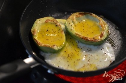 Перевернуть , посыпать солью и перцем. Яйца или яйцо слегка взбить и вылить в углубление авокадо и обжаривать примерно 3 мин.