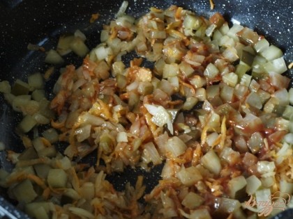 Лук нарезаем кубиками, морковь трём на тёрке. В сковороде разогреваем сливочное масло, обжариваем лук до золотистого цвета, добавляем морковь. Затем солёные огурцы и томатную пасту. Тушим несколько минут.