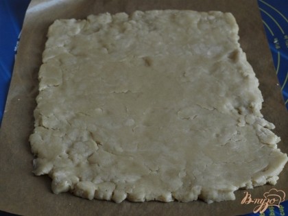 Противень застелить пекарской бумагой,достать тесто из холодильника и раскатать его в пласт около 1 см.