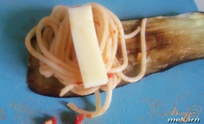 На каждый ломтик баклажана положить брусочек сыра и сверху спагетти. Свернуть рулетик.