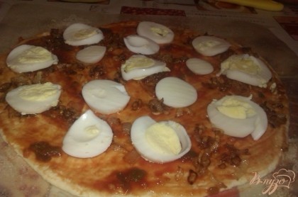 Вареные яйца очищаем и нарезаем кружочками, которые выкладываем на промазанную кетчупом основу для пиццы.