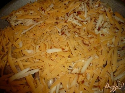 Твердый сыр натираем на крупной терке и распределяем его по всей поверхности мяса с картошкой.