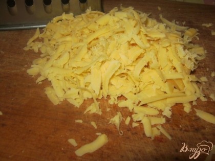 Натереть сыр на крупной терке, половину отложить для посыпки верха, остальное смешать с общей массой.