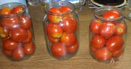 Для начала хорошо промываем помидоры, те которые твердые укладываем в банки. Заливаем банки кипятком, накрываем крышкой и укутываем на время.