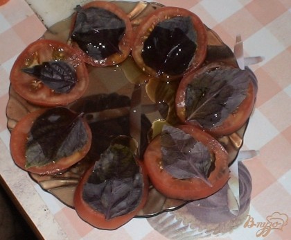 Сбрызгиваем помидор оливковым маслом и на каждое колечко помидора выкладываем по листику базилика. Можно выкладывать базилика и побольше. Кому как нравится, мне же и листика достаточно.
