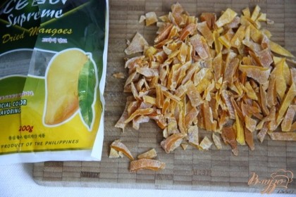 Нарезать сухофрукты или шоколад, орехи (не влажный наполнитель!). Я нашла сушеный засахаренный  манго. Добавить наполнитель в тесто.
