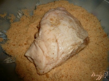 Панировочные сухари высыпаем на плоскую тарелку. Куриные бедра достаем из маринада, кладем в тарелку с панировочными сухарями.