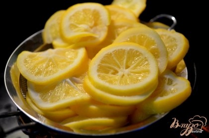 Выложить лимоны в посуду, не реактивную (без содержания меди и алюминия). Не реактивная-это эмаль,пластика,стекло,глина и нержавейка. Залить полностью водой и поставить на медленный огонь на 10 мин. Слить воду и повторить снова.