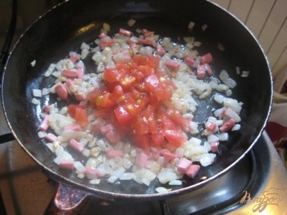 С помидора снять кожицу, нарезать и положить в сковороду, перемешать.