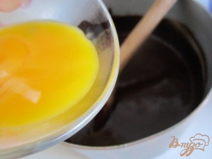Затем в горячую шоколадную массу ввести 2 желтка и хорошо размешать.