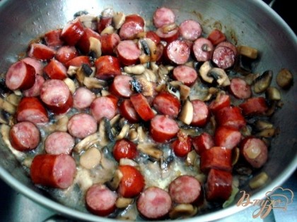 Нарезаем колбасу, её  и грибы слегка обжариваем вместе.