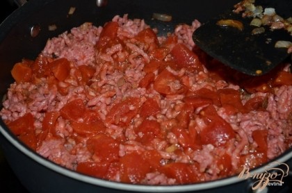 Добавим фарш, разломаем на кусочки, Готовим пока не исчезнет розовый цвет, помешиваем. Затем томаты, соль и перец и 1 стакан воды.