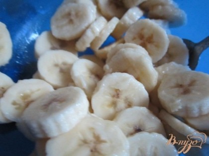 Бананы нарезать на кружочки и полить соком лимона, перемешать и разложить вторым слоем.