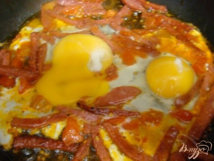 Вбить яйца к обжаренной колбасе и помидорам, обжарить в течении 3 минут