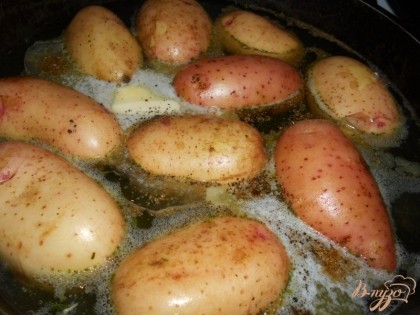 Картофель (желательно небольшой, одинакового размера) хорошо помыть. Прямо в кожуре сложить в толстостенную сковороду (лучше всего подойдет чугунная). Влить в сковороду бульон, чтобы он покрывал картофель на 3/4. Добавить перец, соль, оливковое и сливочное масло и щепотку кориандра.