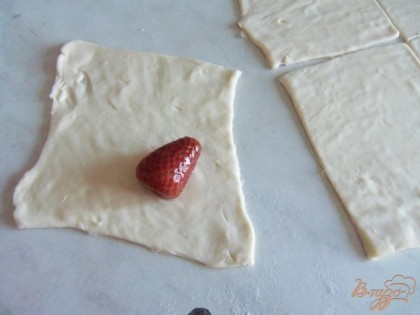 Готовое тесто разморозьте при комнатной температуре. Из теста нарезать квадратики. На каждый квадратик положить ягоду или кусочек фрукта (в оригинале яблоки). И завернуть.