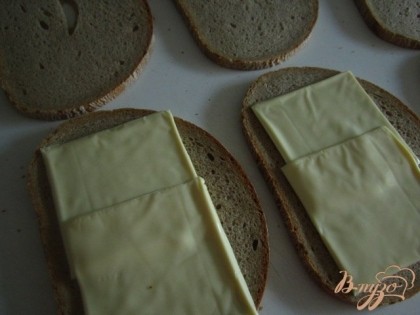Между двумя кусочками хлеба уложить пластинки плавленного сыра.