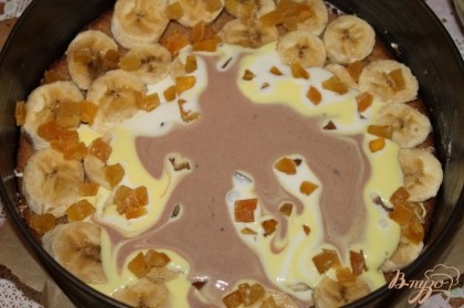 На бананы и цукаты слоями наливаем творожное суфле. На центр торта столовой ложкой сначала наливаем белое суфле, затем желтое и шоколадное.