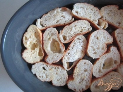 Форму для запекания намазать сливочным маслом.Выложить первым слоем кусочки хлеба, обмакнув только одной (нижней) стороной в яичную смесь.