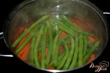 Зеленую фасоль и морковь положить в кастрюлю с горячей водой,чтоб вода лишь накрыла овощи. Варим до мягкого состояния фасоль и морковь,примерно 5-8 мин.под закрытой крышкой. Затем воду слить.