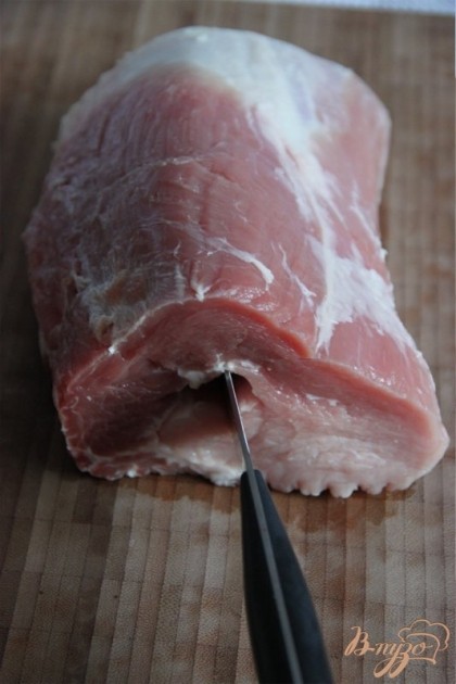 При помощи длинного тонкого ножа сделать сквозное отверстие в центре свиной корейки.  Ширины отверстия должно хватить для тонкой палки колбасы.