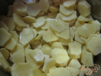 Картофель очистить от кожуры, нарезать тонкими пластами и уложить на дно кастрюли.