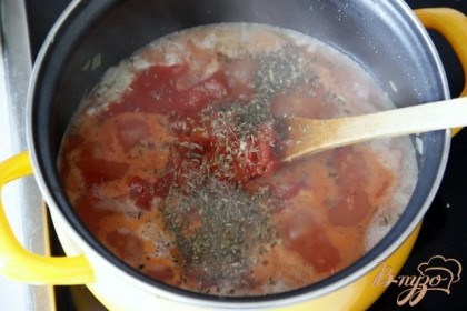 Добавить томаты в собственному соку, вместе с соком, сушеный тимьян и орегано. Варить на небольшом огне до готовности, пока рис не впитает всю жидкость.