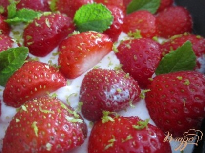 Достаем торт из холодильника.По всей поверхности разложить половинки ягод, листики мяты и посыпать цедру лайма.
