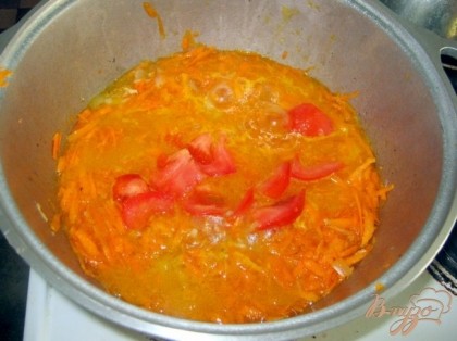 Затем в казан поверх мяса добавить морковь и нарезанный кусочками помидор. Подлить немного воды и продолжать тушить еще минут 10.
