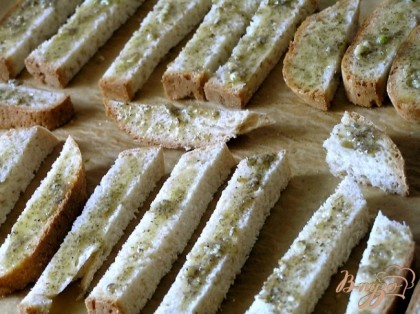 Кусочки хлеба разложить на противне, застеленном бумагой для выпечки, смазать ароматным маслом.