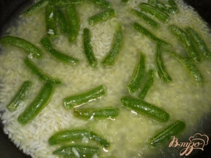 Добавить к рису фасоль, обжарить еще пару минуть. Влить воду (овощной бульон), чтобы покрыла рис.