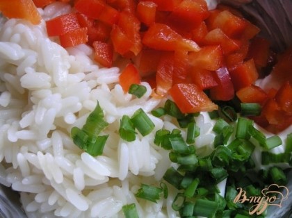 К остуженному рису добавить творожный сыр, нарезанный сладкий перец и зелень, перемешать.