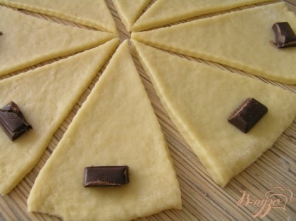 Тесто разделить на 2 части, каждую раскатать, нарезать треугольниками, на каждый треугольник положить по кусочку шоколада,